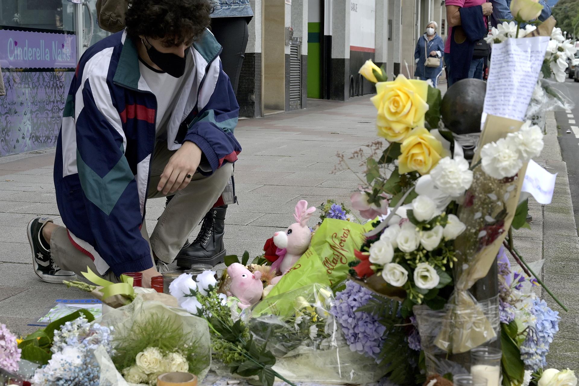 Un joven se arrodilla ante el altar colocado en la acera donde fue golpeado Samuel, el joven asesinado en A Coruña | M. DYLAN EP