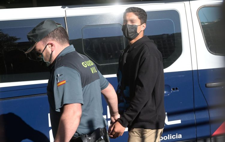 Uno de los investigados por la muerte de Samuel Luiz, esposado y acompañado de un agente de la Policía Nacional, a su entrada al Juzgado de Instrucción número 8 de A Coruña | EP