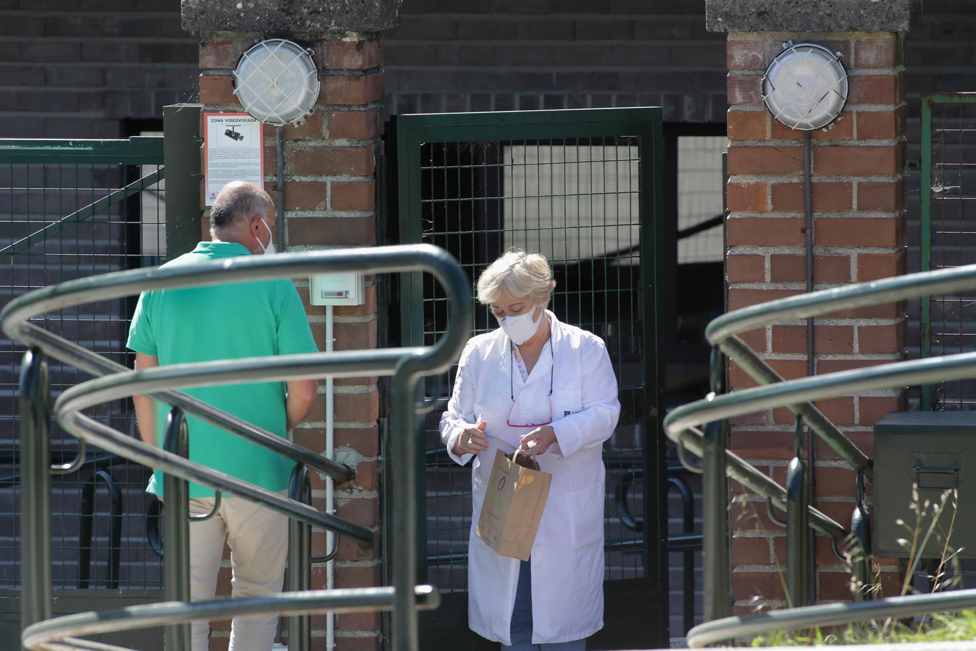 Una trabajadora atiende a un familiar en la puerta de la residencia de As Gándaras de Lugo. | EUROPA PRESS