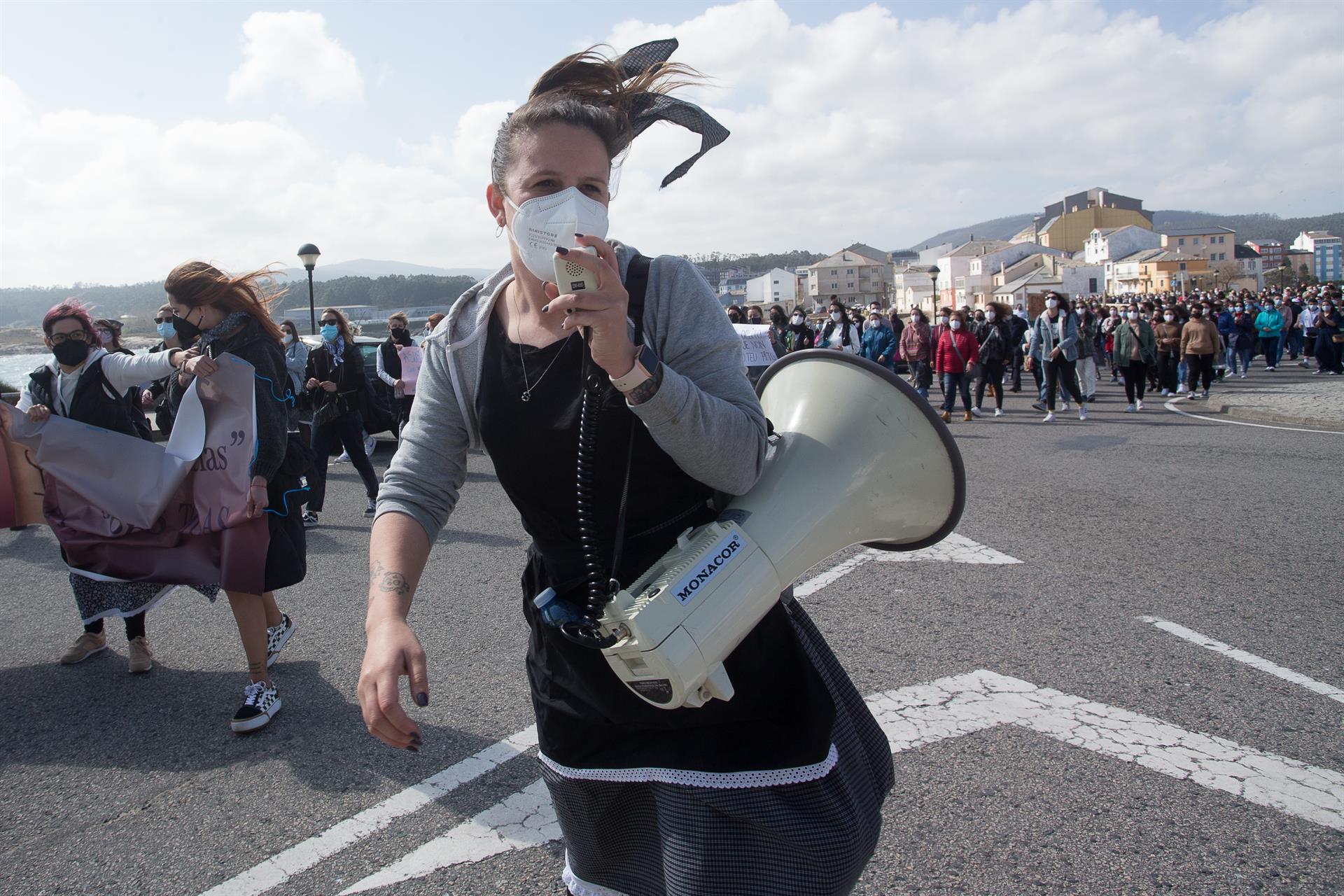 Una mujer sostiene un megáfono durante una manifestación en apoyo a las 87 mujeres que en 2019 fueron grabadas “sin autorización”, a 4 de abriil de 2021, en la playa de Torno, en San Cibrao, Lugo, Galicia. | EUROPA PRESS