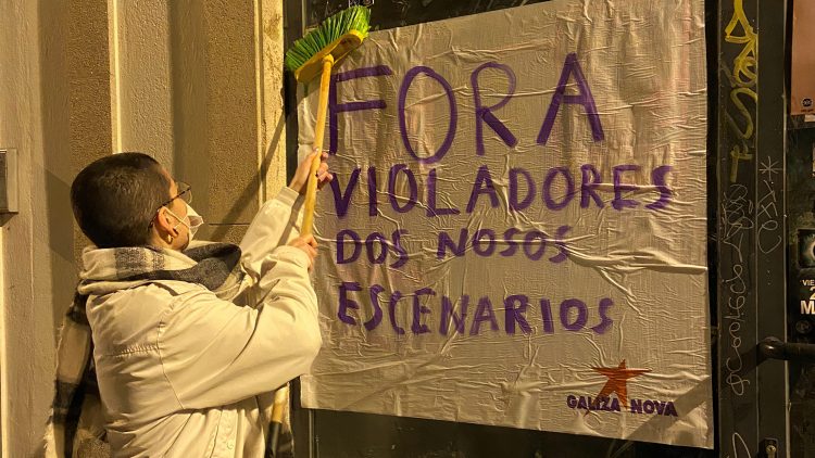Una mujer pega un cartel en la concentración | GALIZA NOVA