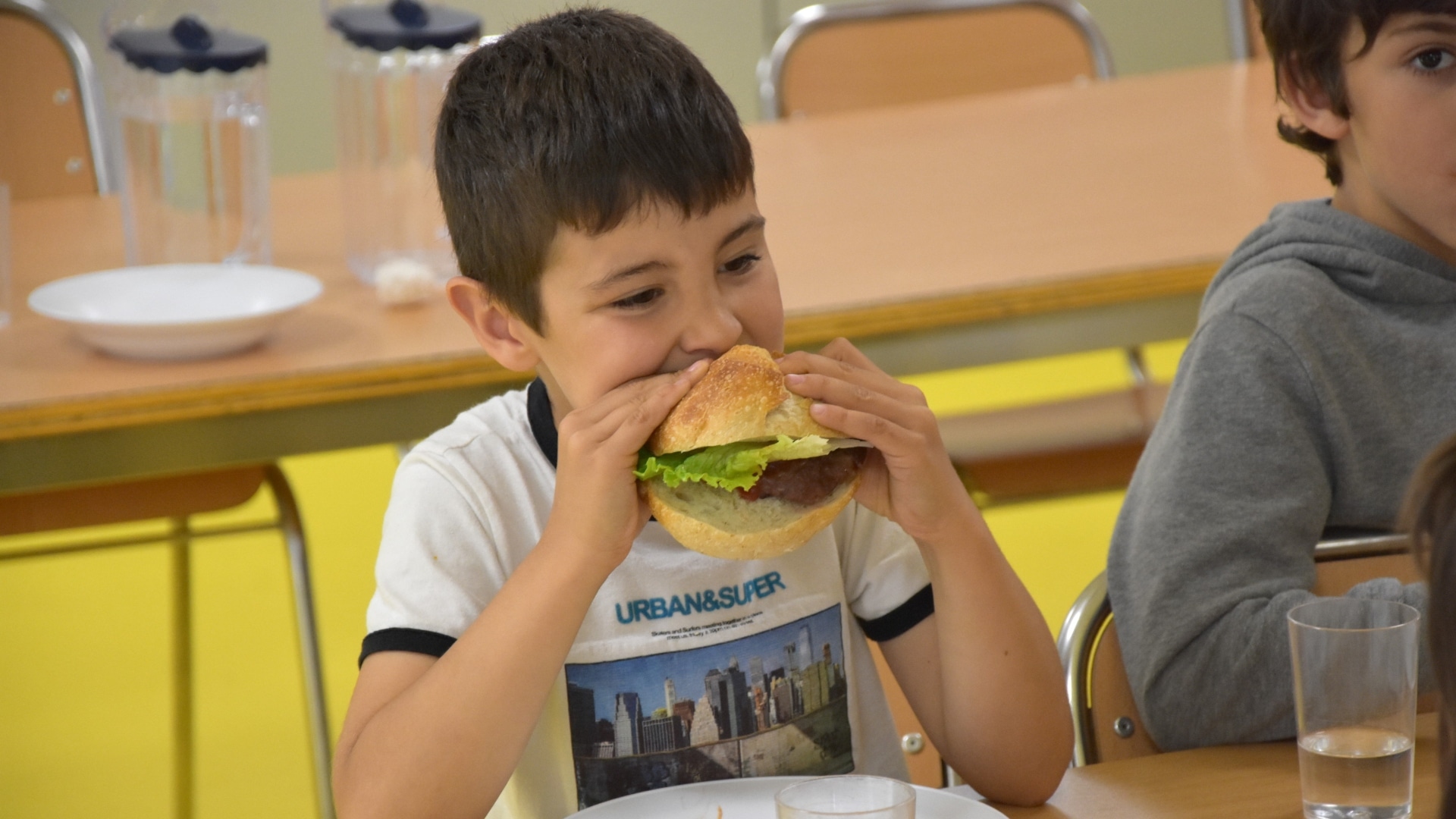 Un alumno come la hamburguesa de fin de curso en un comedor escolar de Ames | CONCELLO DE AMES