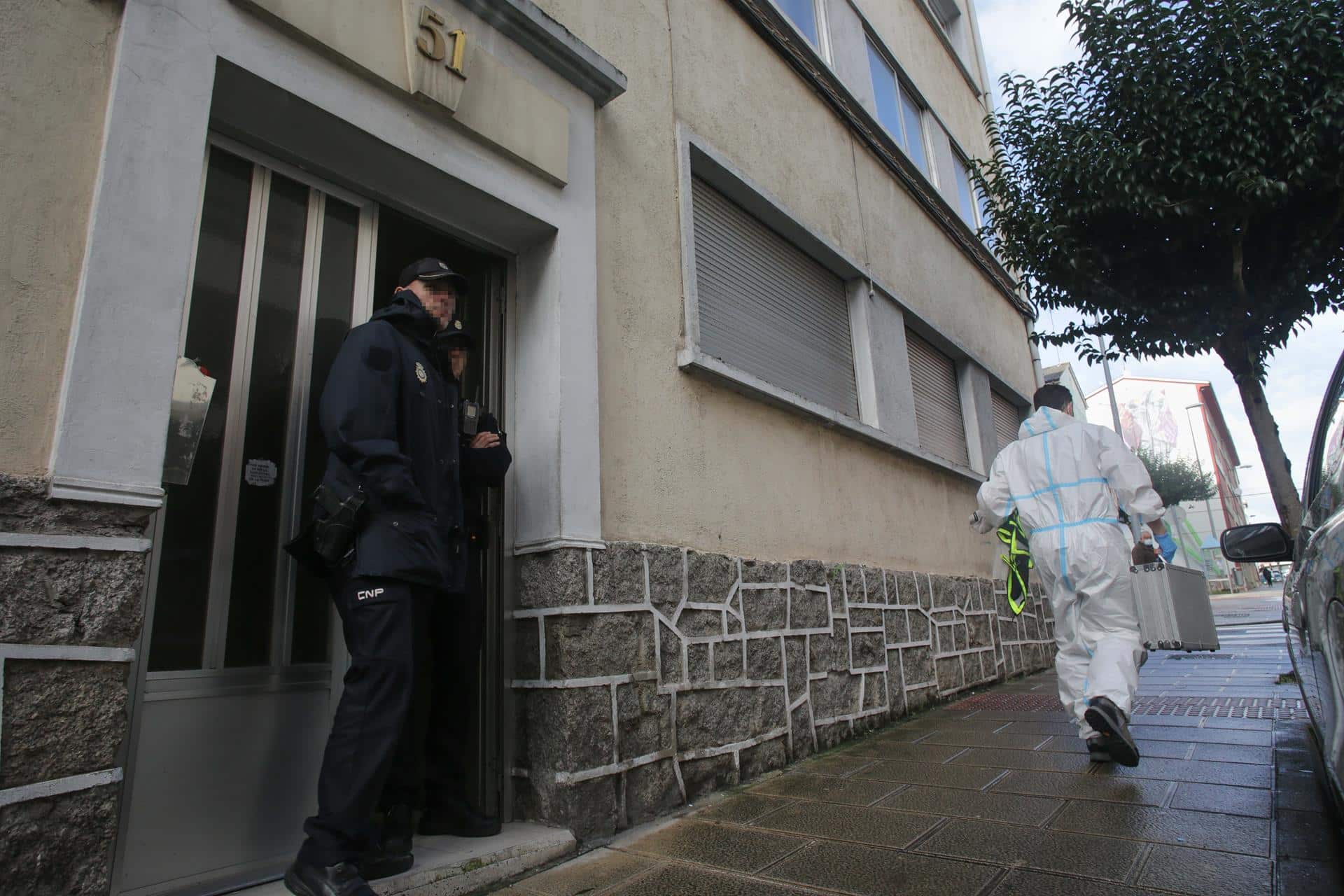 Un agente de Policía Nacional en la puerta de la vivienda donde han hallado muerta a una mujer de 42 años | Carlos Castro, EP