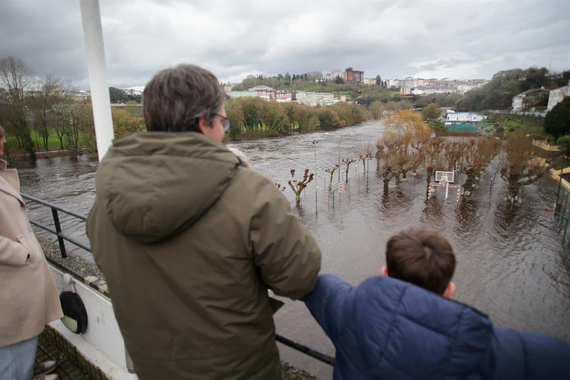 Un hombre y un niño observan la crecida del río Miño debido a las lluvias, en Lugo el pasado diciembre | EP