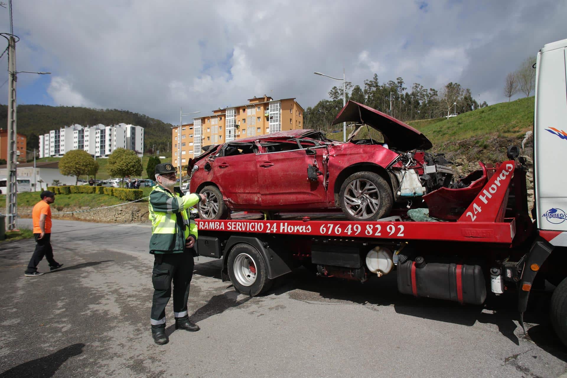 Un Guardia Civil vigila la retirada del coche siniestrado, en el accidente, por una grúa| EP