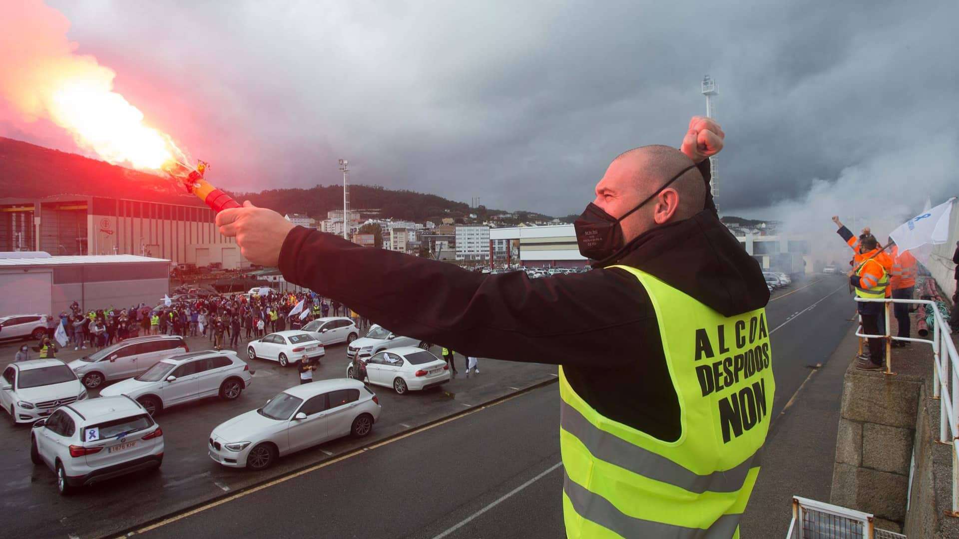 Un hombre sostiene una bengala encendida durante una caravana de vehículos de trabajadores de Alcoa en Burela | EP