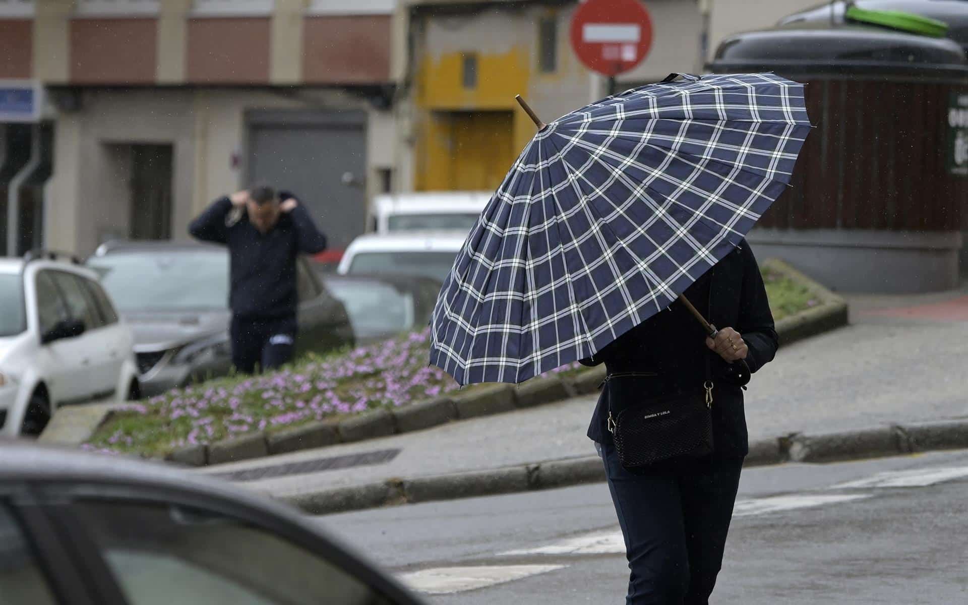 Imagen de archivo de una mujer protegiéndose de la lluvia con un paraguas en A Coruña | EP