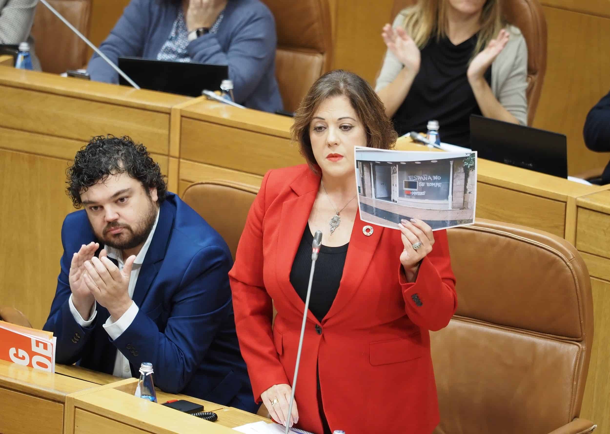 La viceportavoz del Grupo Socialista, Begoña Rodríguez Rumbo muestra a Alfonso Rueda una imagen de las pintadas en la sede socialista de Ferrol
