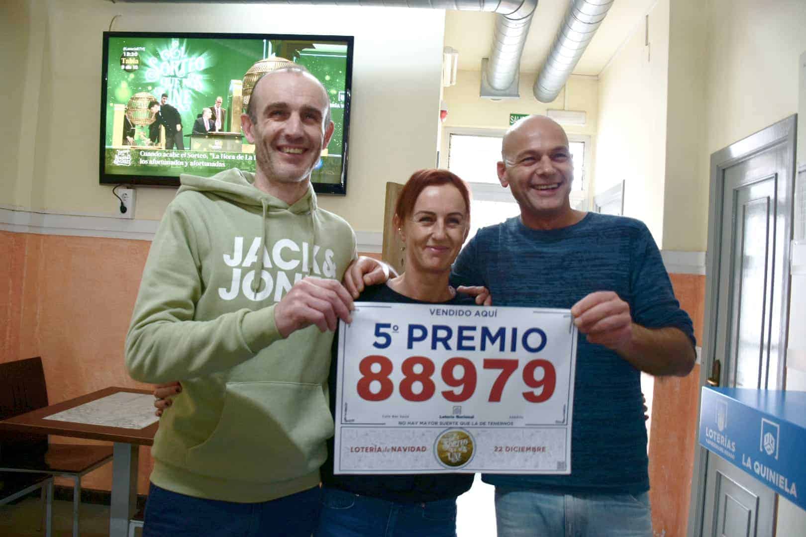 Emilio, Merce y Roberto, del Café Bar Seijo, sujetando el cartel del quinto premio de la Lotería de Navidad | ENFOQUES