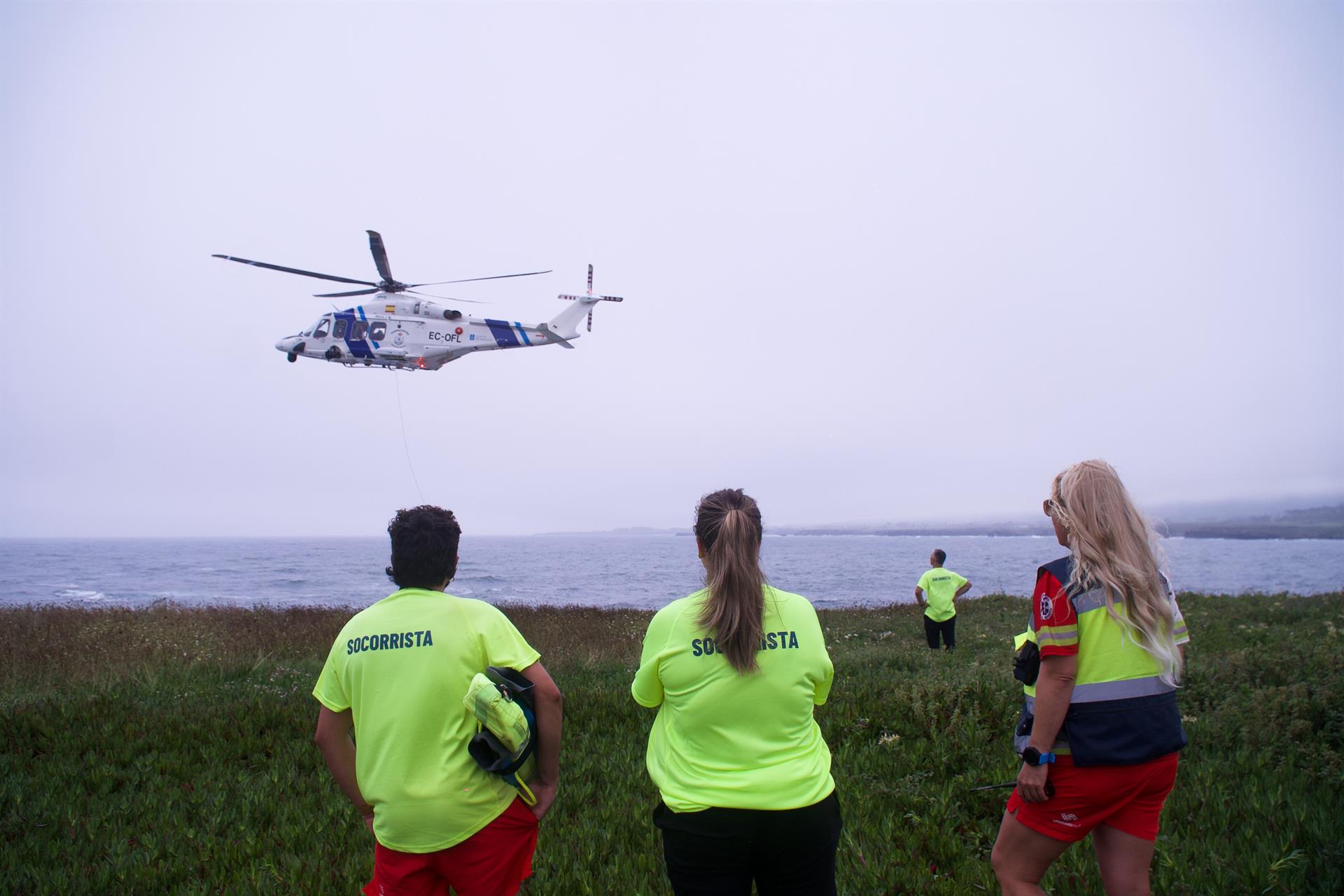 Varios socorristas observan a un helicóptero rescatando a un varón joven en la Punta do Castro, a 28 de julio de 2024, en San Pedro de Benquerencia, Barreiros, Lugo | EP