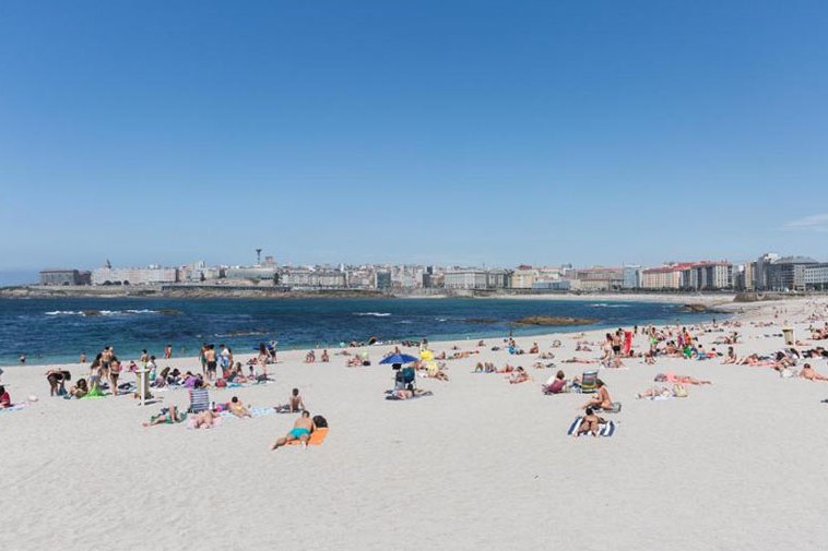 Gente disfrutando en el arenal de la playa del Orzán | CEDIDA