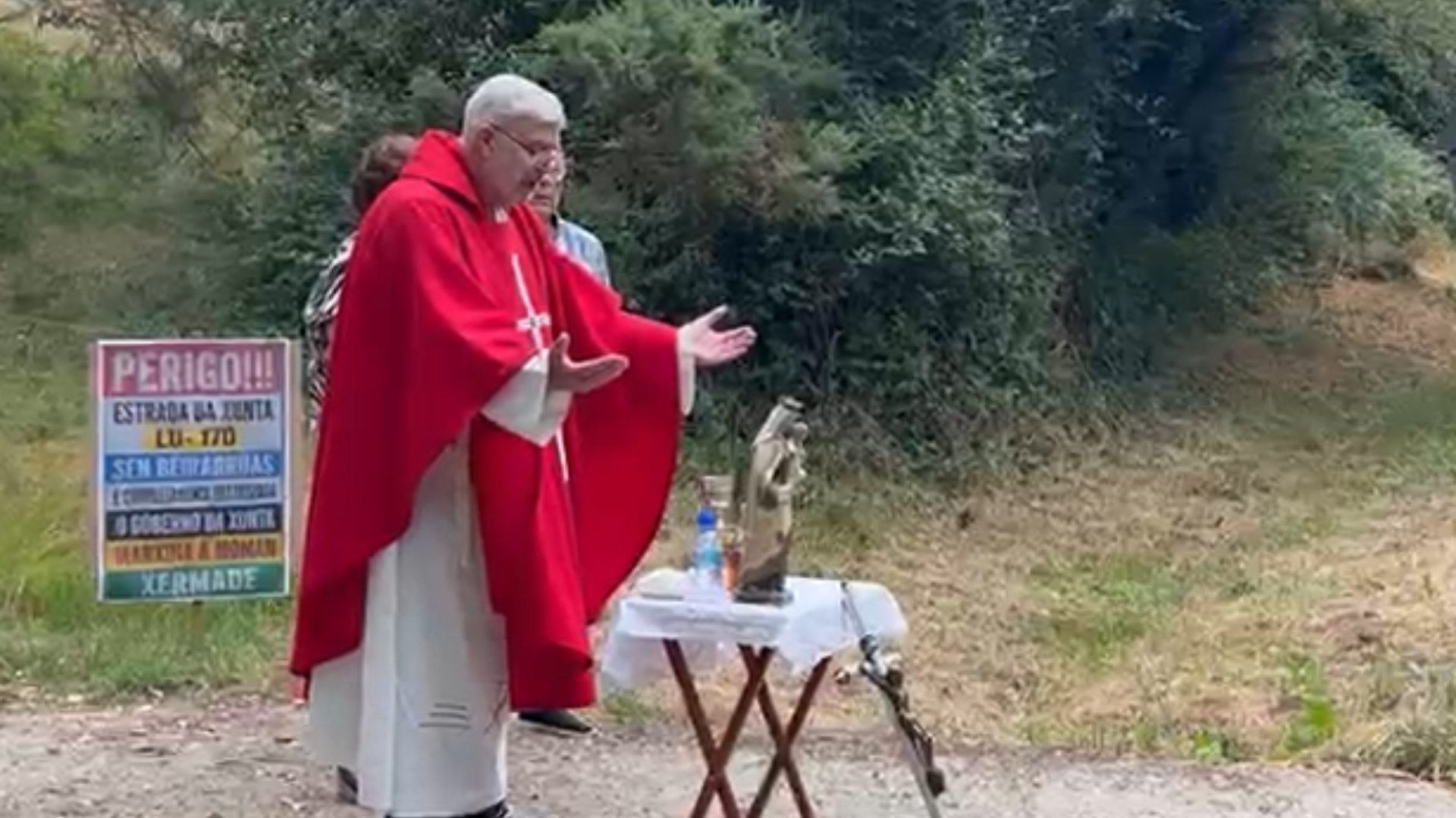El párroco de Momán, Luis Ángel Rodríguez Patiño, durante la misa oficiada en plena carretera esta mañana | Enfoques.gal